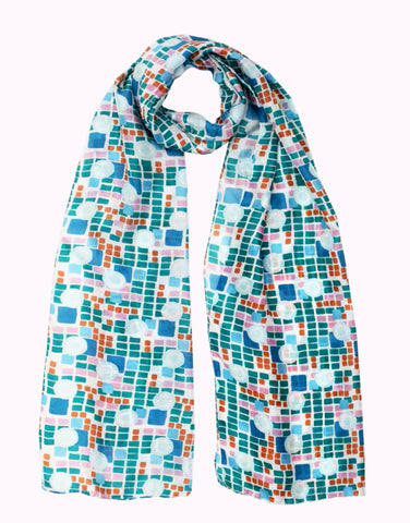 A long silk scarf with blue and green geometric pattern which also features lighter blue concentric circles and red and orange highlight checks